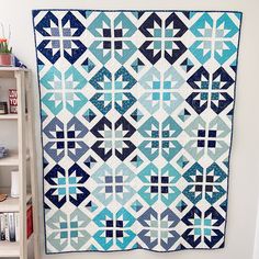 a blue and white quilt hanging on the wall next to a book shelf filled with books