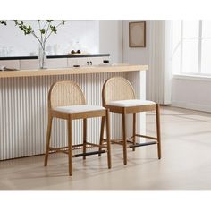 two stools sitting in front of a counter with a vase on top of it