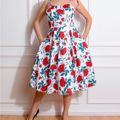 Della Floral Swing Dress, With A Stand Out Floral Print Of Bright Roses And Dark Petals On A Fresh White Base. With A Gorgeous Sweetheart Neckline Framed By Tie Shoulder Straps, This Style Is A Summer Stand Out Piece. The Fitted Bodice Which Leads Into A Swinging Skirt Is Reminiscent Of The 1950s Which We Hold Dear In Our Hearts. We Of Course Added Our Favourite Hidden Side Pockets To Add That Extra Ease To Your Day. Made Using A Comfortable And Stretchy Cotton, This Style Is Perfect For Going A Bright Roses, Hearts And Roses, London Dresses, The 1950s, Fitted Bodice, Swing Dress, Sweetheart Neckline, Shoulder Straps, Bodice