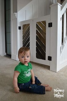 a small child sitting on the floor in front of a white door and some stairs