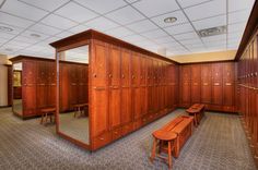 an empty locker room with wooden benches and mirrors on the wall in front of it