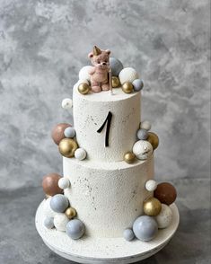 a three tiered cake decorated with balls and a cat figurine on top