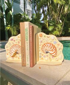 two bookends made out of books sitting on a ledge next to a pool