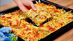 someone taking a slice of vegetable casserole from a pan