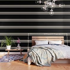 a bedroom with black and white stripes on the wall behind the bed is a chandelier