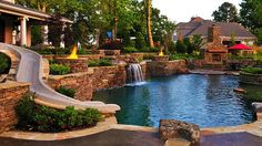 an outdoor pool with waterfall and fire pit