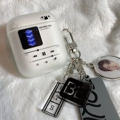 an mp3 player with a keychain attached to it sitting on a white blanket