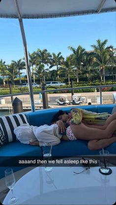 a woman laying on top of a blue couch next to a table with drinks in front of her