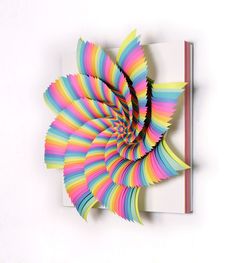 a spiral design made out of colored paper on a white surface with a red pencil