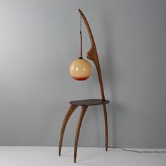 a lamp that is sitting on top of a wooden stand in front of a gray wall