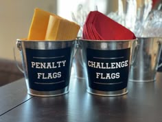 two metal buckets with napkins in them sitting on a table next to each other