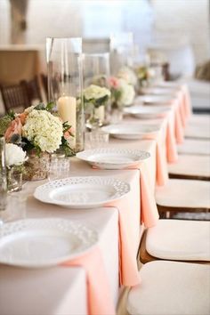 a long table with white plates and flowers on it