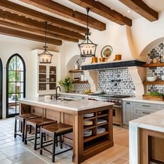 a large kitchen with lots of counter space and wooden beams on the ceiling, along with two stools