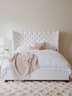 a white bed sitting in a bedroom on top of a carpeted floor next to a window