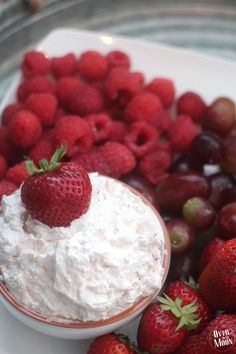 a bowl filled with strawberries, grapes and whipped cream