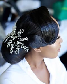 a woman with long black hair wearing a white shirt and a flower in her hair