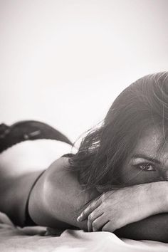 a woman laying on top of a bed next to a white wall