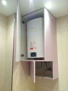 a white tank mounted to the side of a wall next to a mirror in a bathroom