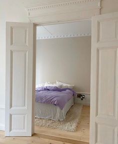 an open door leading to a bedroom with a bed in the corner and a rug on the floor