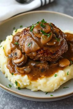 mashed potatoes topped with mushrooms and gravy on a plate