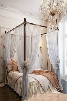 a canopy bed with curtains and a chandelier