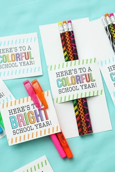 four colorful school year cards with pencils and markers in them on a blue surface