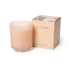 a candle sitting next to a box on a white surface with the words illume written in it