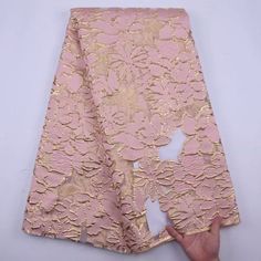 a pink and gold brocaded cloth with hand pointing at it