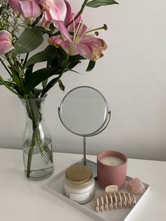 a vase filled with pink flowers sitting on top of a table next to a mirror