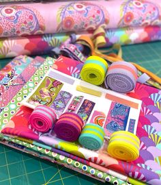 several rolls of colorful fabric sitting on top of a cutting board next to each other