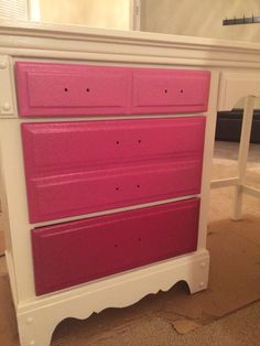 a white dresser with pink drawers on top of it in a room that has carpeted flooring