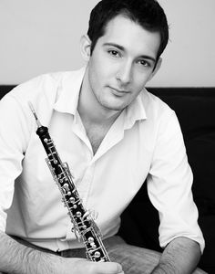 a man sitting on a couch with a flute in his hand and looking at the camera