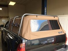 the back end of a black truck with a tan cover on it in a garage