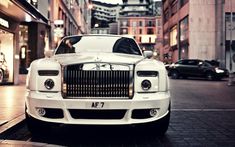 a white rolls royce parked on the side of a street