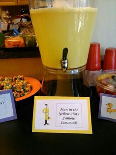 a table topped with plates and cups filled with food next to a drink dispenser