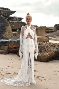 a woman standing on top of a sandy beach wearing a white dress and headpiece