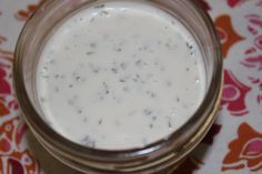 a glass jar filled with white liquid sitting on top of a floral tablecloth covered table