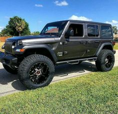 a black jeep parked on the side of a road next to a grass covered field