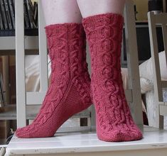 a woman's legs wearing red socks and knee high socks with cabled design