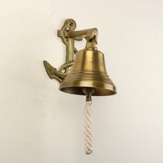 an old brass bell with a rope hanging from it's side on a white wall