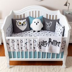 a white crib with harry potter themed bedding and owl pillows on it's sides