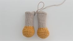 two crocheted yellow and gray mittens hanging from a string on a white surface