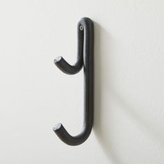 an iron hook on the wall is hanging from it's side and has two hooks attached to it