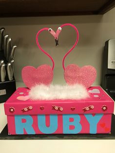 a pink box with two flamingos on it and the words ruby written in blue