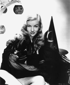 black and white photograph of a woman sitting in front of a wall with clocks on it