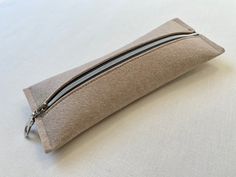 "Made with love from the San Francisco Bay Area! This handmade makeup bag is made from a single piece of thick (2mm), high-quality felt that keeps its shape even with daily use. The pouch is a beige wheat color, secured with a smooth zipper made from silver hardware and contrasting gray trim. An elegant accessory perfect for minimalists. The pouch can be used to hold makeup, brushes, pencils/pens, or other small items. Perfect for people on the go, students, artists, minimalists or anyone who ne Everyday Rectangular Pencil Case With Zipper, Everyday Rectangular Pouch With Pen Slots, Modern Rectangular Pencil Case For Everyday Use, Beige Pencil Case With Pen Slots For Daily Use, Beige Pencil Case With Pen Slots, Rectangular Everyday Pouch With Pen Holders, Rectangular Pencil Case With Zipper Pocket, Rectangular Beige Pencil Case For Daily Use, Beige Zipper Pouch Pencil Case For Daily Use