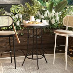 two chairs and a table with plants in the background