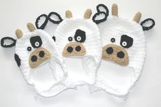 three crocheted cow hats with black and white ears