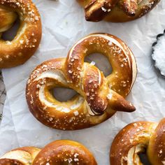 several pretzels are sitting on wax paper with salt sprinkled around them