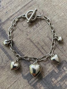 Puffy heart charms vintage silver-tone bracelet, very cute with graduated shiny heart charms and a toggle clasp with Korea stamp.  This item is used or estate and may have scratches and wear appropriate to it's age. I will do my best to describe anything I can see that is out of the ordinary. I consider photos as a part of the description. Metal Heart Bracelet With Toggle Clasp, Silver Metal Heart Bracelet With Charms, Nickel-free Heart-shaped Metal Charm Bracelet, Silver Heart Charm Chain Bracelet, Silver Metal Chain Bracelet With Heart Charm, Silver Heart-shaped Bracelet With Toggle Clasp, Silver Heart Bracelet With Toggle Clasp, Silver Metal Chain Bracelet For Valentine's Day, Valentine's Day Silver Metal Chain Bracelet